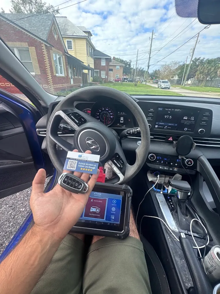 We Do Locksmith technician in the driver's seat of a car with a diagnostic programmer