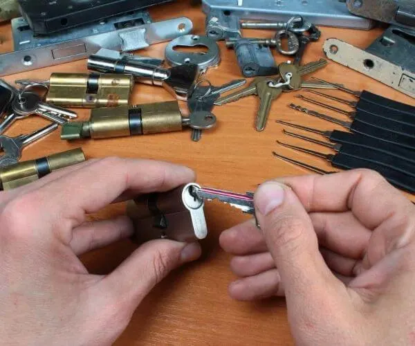 Locksmith's hands rekeying a lock cylinder on a workbench