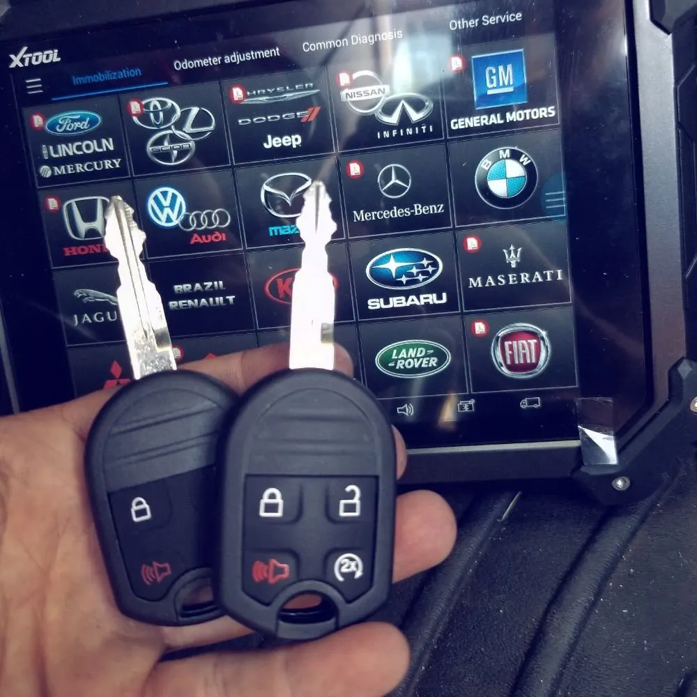 Two freshly cut remote-head car keys held in front of a key programmer in a We Do Locksmith van